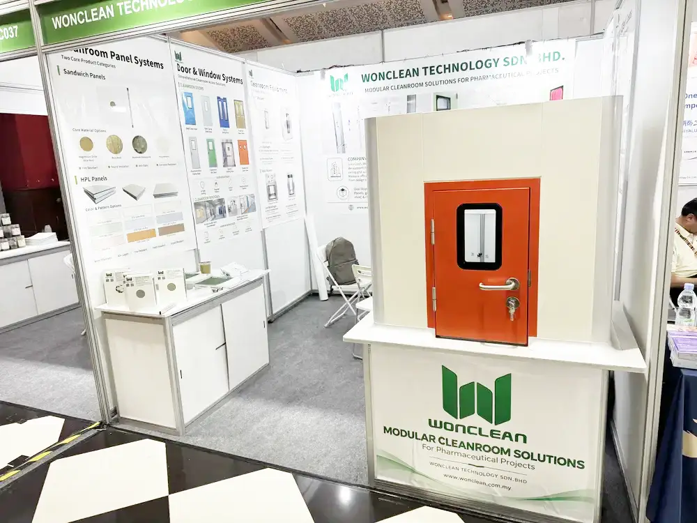 Orange cleanroom door sample installed within a white wall panel demonstration at the WONCLEAN booth